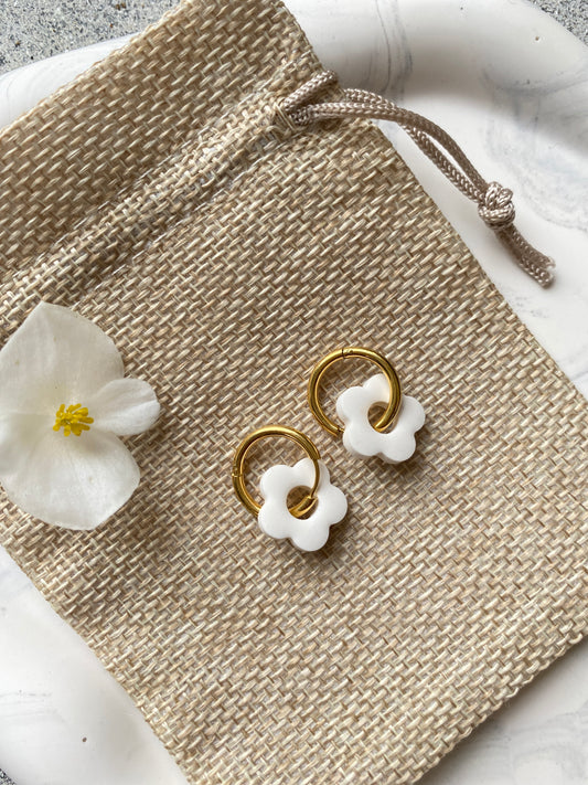 Photo de boucles d'oreilles fleurs blanches en résine écologique sur pochon