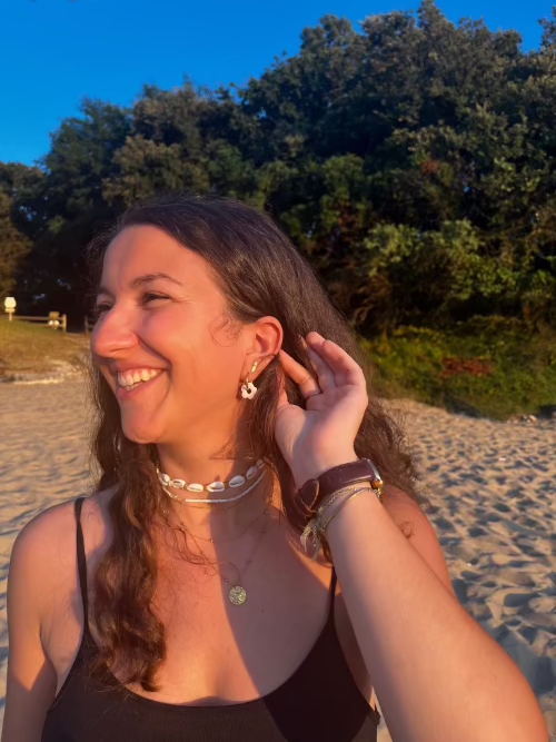 Photo d'une femme à la plage portant les boucles d'oreilles fleurs blanches en souriant
